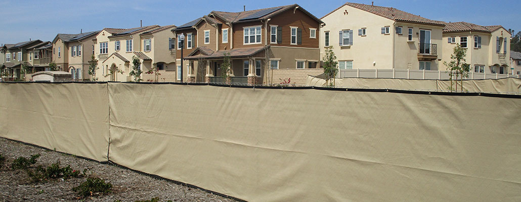 Temporary fence rental near Lone Star, Fresno, California with beige privacy screen in front of homes.