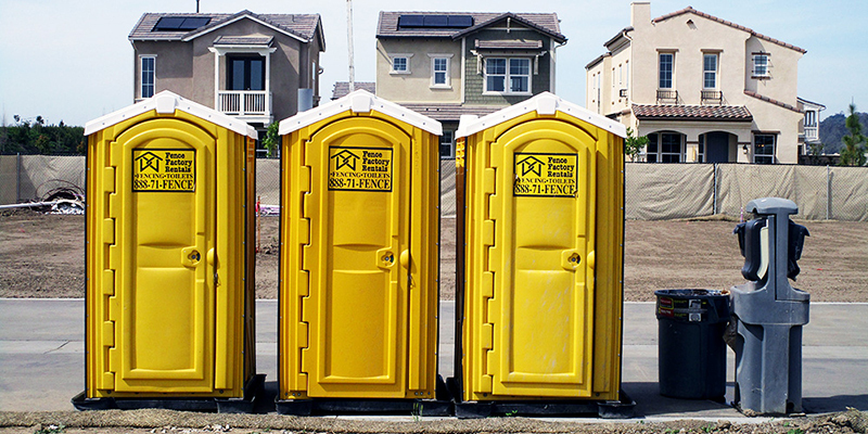 Three yellow porta potty rentals near Avila Beach, California, supplied by Fence Factory Rentals.